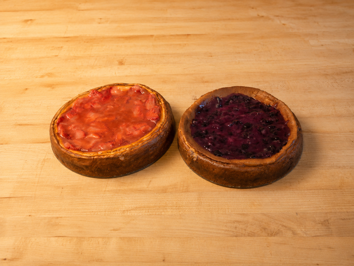 Strawberry and blueberry cheesecakes side by side
